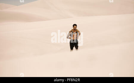 Atleta maschio in esecuzione sulle dune di sabbia. L'uomo facendo esercizio in esecuzione nel deserto. Foto Stock