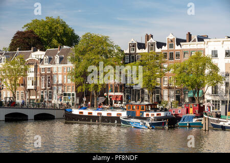 AMSTERDAM, Paesi Bassi - 6 agosto 2018: una grande casa barca sul fiume Amstel con le tradizionali case sul canale. Foto Stock
