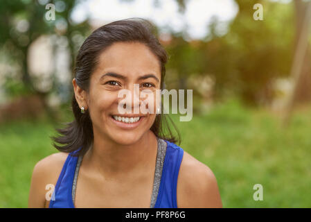 Piuttosto sorridente latina donna in estate parco ritratto di sfondo Foto Stock