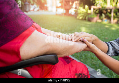 Custode spingendo senior donna in sedia a rotelle Foto Stock