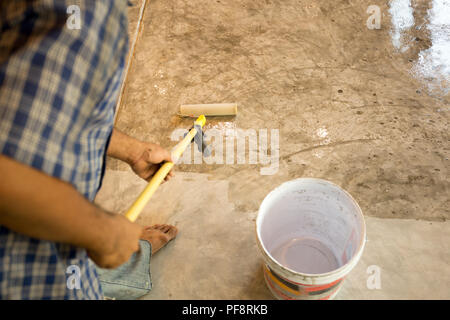 Lavori di laccatura pavimenti in calcestruzzo usando il rullo per rivestire Foto Stock