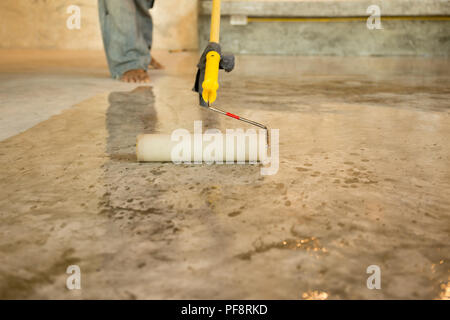 Lavori di laccatura pavimenti in calcestruzzo usando il rullo per rivestire Foto Stock