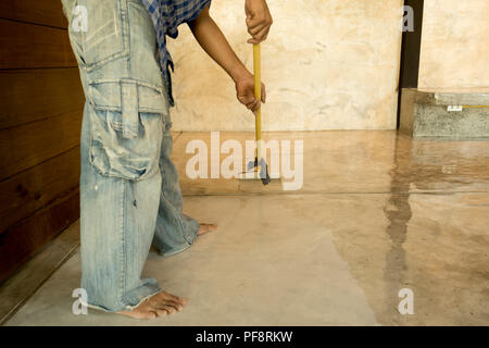 Lavori di laccatura pavimenti in calcestruzzo usando il rullo per rivestire Foto Stock