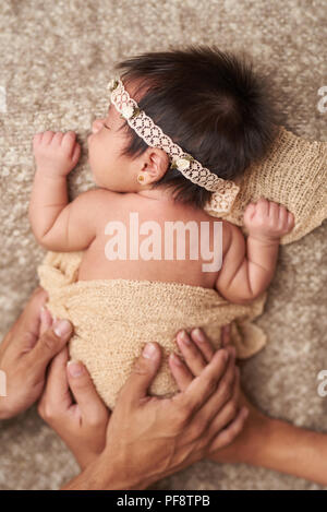 Prendersi cura del neonato. I genitori le mani coprire sleeping baby Foto Stock