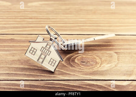 Portachiavi con il simbolo della casa e le chiavi su sfondo di legno,immobiliare di concetto Foto Stock