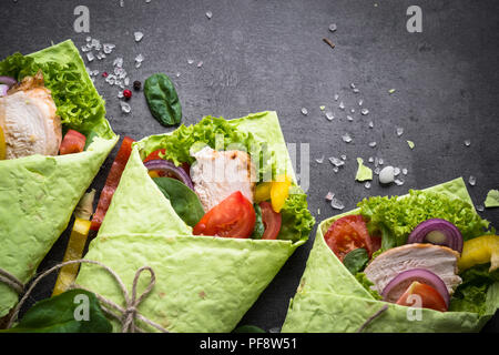 Verde spinaci tortilla con pollo e verdure. Vista dall'alto sul nero ardesia tabella con copia spazio. Snack sani. Foto Stock