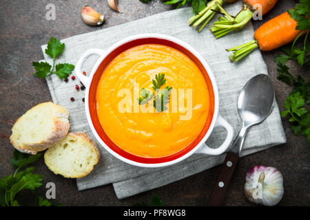 La carota Crema di zucca-zuppa su pietra scura tabella. Vegetariano zuppa di verdure. Vista dall'alto. Foto Stock