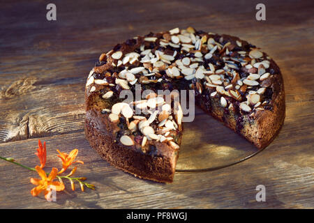 Una sana fatti in casa a base di pane alla banana, senza zucchero con la farina di mandorle, le bacche e le mandorle in una tabella, artistico in stile country food still life su legno rustico Foto Stock