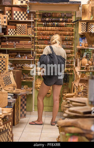 Attraente giovane donna indossa pantaloncini in un negozio di articoli da regalo scegliendo negozio di souvenir a Kerkyra, Corfù, Grecia. Foto Stock