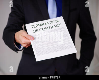 Immagine ritagliata di imprenditore che indossa una tuta e tenendo un foglio di carta per arrivare dal boss, con la risoluzione del contratto il testo su di esso, in uno sfondo sfocato Foto Stock
