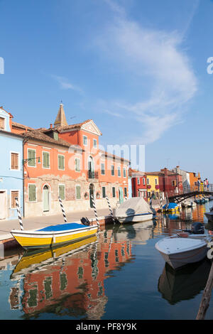 Tramonto nel colorato villaggio di pescatori sull'isola di Burano, Venezia, Veneto, Italia con turisti sul ponte sul canal grande e con le riflessioni e le barche Foto Stock