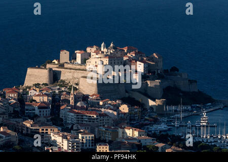 Immerso nella tarda sera la luce del sole è la cittadella di Calvi arroccato su uno sperone di roccia affacciato sul Calvi città vecchia e Calvi baia sulla costa nord-occidentale della Corsica Foto Stock