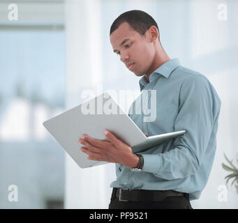 Grave Manager che lavora su un computer portatile in piedi in ufficio Foto Stock