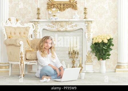 Curly blonde ragazza adolescente in abbigliamento casual seduto sul pavimento Foto Stock