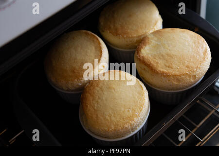 Quattro soufflé in ceramica bianca vaso (ramekin) su forno, fatti in casa Foto Stock