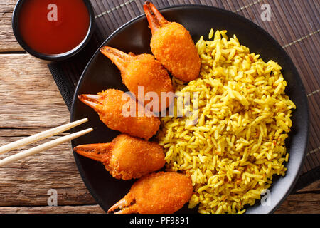 Fritte chele di granchio nel pangrattato di surimi con il piccante riso giallo close-up su una piastra su un tavolo. Parte superiore orizzontale vista da sopra Foto Stock