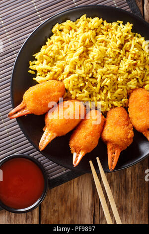 Porzione di chele di granchio fritte in panatura servito con riso e salsa di pomodoro close-up su una piastra su un tavolo. Verticale in alto vista da sopra Foto Stock