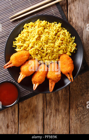 Fritte chele di granchio nel pangrattato di surimi con il piccante riso giallo close-up su una piastra su un tavolo. Verticale in alto vista da sopra Foto Stock