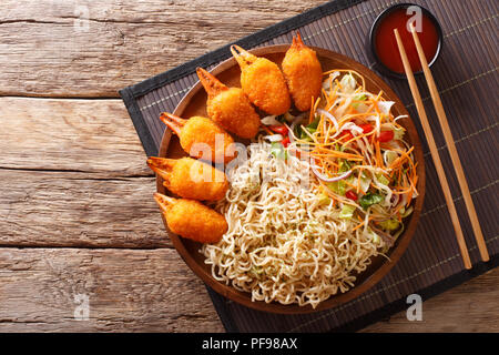 Delizioso fast food chele di granchio in panatura con egg noodles e fresca insalata di verdure close-up su una piastra su un tavolo. parte superiore orizzontale vista da sopra Foto Stock