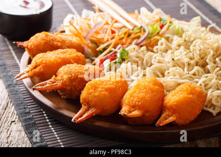 Cucina cinese: chele di granchio in panatura con egg noodles e fresca insalata di verdure close-up su una piastra su un piano orizzontale. Foto Stock