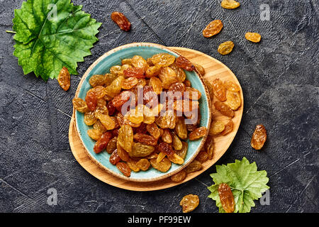 Giallo grande uva passa nera su sfondo di calcestruzzo. Vista dall'alto di uve secche. Foto Stock