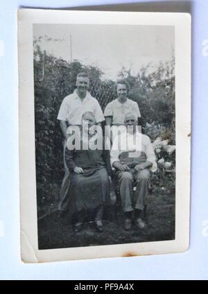 Storia sociale - bianco e nero vecchia fotografia che mostra quattro persone di mezza età di persone in un giardino Foto Stock