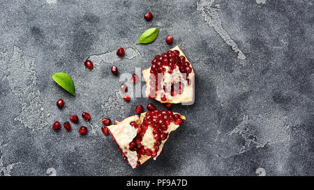 Melograno frutta con semi su sfondo grigio con copia spazio. Vista dall'alto. Foto Stock