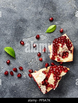 Melograno frutta con semi su sfondo grigio con copia spazio. Vista dall'alto. Foto Stock