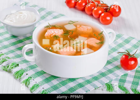 Zuppa di salmone con verdure e aneto in una ciotola bianco su una tovaglia su un tavolo rustico,vista da sopra, close-up Foto Stock