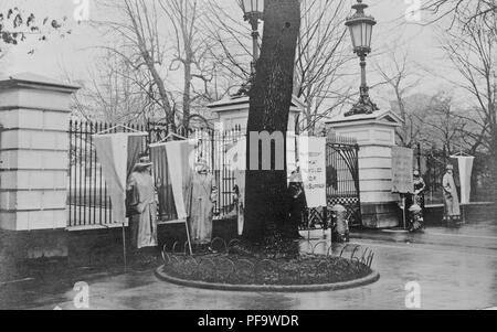 Fotografia in bianco e nero che mostra la 'silenzio sentinelle, ' membri di Alice Paul donna Nazionale Partito di suffragio, picchetti di fronte una recinzione al di fuori della Casa Bianca, 1917. () Foto Stock