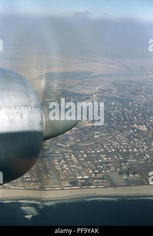 Vista aerea di fronte a nord dei quartieri di Edgemere, Wavecrest e Bayswater, sulla penisola Rockaway nel sud del Queens, a New York City, Giugno 1959. Il motore propulsore di un Swissair DC 7C aeromobile è visibile in primo piano a sinistra, crociera al di sopra del litorale atlantico. () Foto Stock