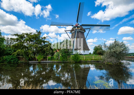 Mulino a vento olandese si riflette nell'acqua e cielo nuvoloso cielo blu. Foto Stock