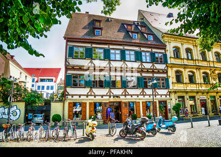 Tra architettura bavarese, scooter sono parcheggiate al di fuori di una birra Keller a Ulm in Germania Foto Stock