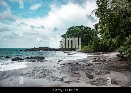 Spiaggia vuota in una caletta rocciosa con sabbia nera sulla costa della provincia Puntaarenas in Costa Rica, nei pressi di Montezuma Foto Stock