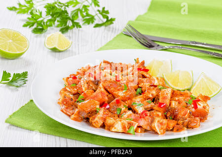 Brasato di orecchie di maiale o Oreja de cerdo con spezie, peperoncino, pezzi di calce cosparsa di prezzemolo sul piatto bianco su legno vecchio tavole, vista dall'alto Foto Stock