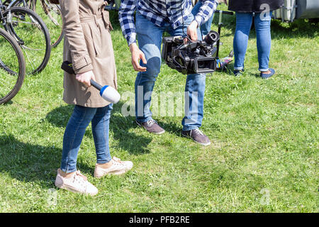 TV reporters lavorare all'esterno. Journalsit e cameraman rendendo report in strada sulla luminosa giornata di sole Foto Stock