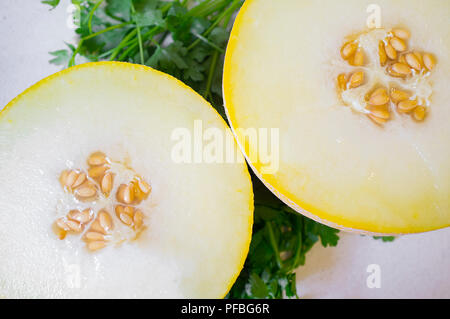 Melone Galia pausa a metà su sfondo di prezzemolo. Primo piano Foto Stock