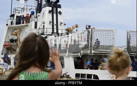 Una giovane ragazza onde da suo padre il guardacoste decisivi in quanto la taglierina si prepara a moor.La mossa decisiva da Pascagoula, Mississippi, al suo nuovo homeport in Pensacola, Florida, Giugno 5, 2018. Stati Uniti Coast Guard Foto Stock