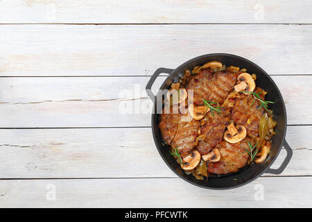 Delizioso filetto di maiale tagliato a fettine, piatti alla griglia e stufati con cipolla. funghi, semi di vino bianco secco e spezie in stufato di ferro pan, facile ricetta, vista dal Foto Stock