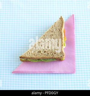 Formaggio e insalata panino tagliato in forma triangolare sul tovagliolo rosa blu sulla tavola a scacchi panno. Foto Stock