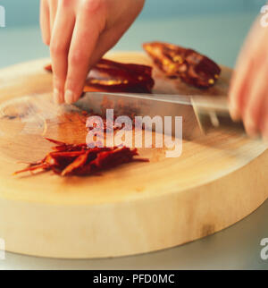 Peperoncino rosso tritato essendo su un tagliere di legno, movimento sfocato Foto Stock