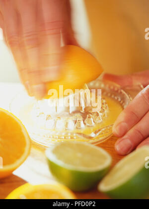 Succo di limone estratto con il limone premere, calce e metà di colore arancione in primo piano. Foto Stock