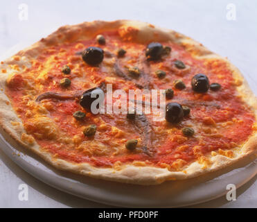 Pizza tonda con base sottile e sottile crosta croccante, conditi con salsa di pomodoro e olive intere, acciughe, capperi e formaggio Foto Stock