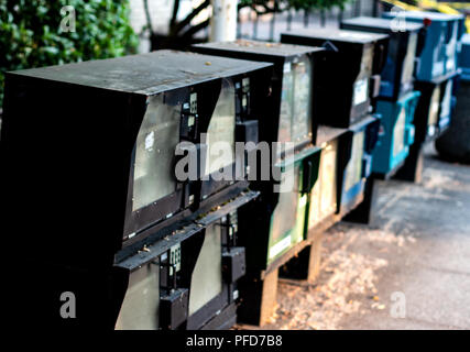 Erogatore di giornale distributori automatici in una fila su un marciapiede Foto Stock