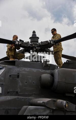 Sgt. Jamie Gil (sinistra) e Sgt. Jose Fimbrez (destra) assegnato alla Task Force Viper° Battaglione, 3° Reggimento di aviazione, XII Combattere la Brigata Aerea condotta di operazioni di manutenzione su un AH-64 Apache elicottero durante lo sciopero di Saber 18 a Bemowo Piskie Area Formazione in Orzysz, Polonia, 11 giugno 2018. Foto Stock