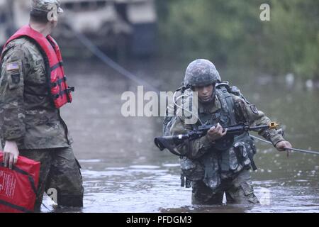 Stati Uniti La riserva di esercito di Spc. Nicolas Cholula-Lopes, un cameraman di combattimento che rappresentano il segnale 311th comando (teatro), attraversa l'acqua durante la ruck marzo evento al 2018 U.S. La riserva di esercito guerriero migliore concorrenza a Fort Bragg, Carolina del Nord, 12 giugno 2018. L'estenuante e multiforme della concorrenza negli Stati Uniti valutati La riserva di esercito di soldati nel ruck marzo, l'eccellenza in concorrenza gamma pistola, forze armate tedesche Proficiency BADGE e alcuni altri eventi con più sfide a venire. Foto Stock