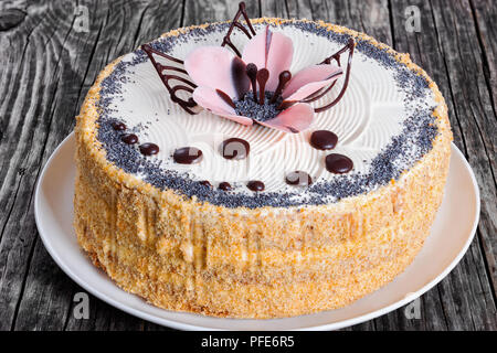 Lussureggianti di semi di papavero, noci e uvetta pan di spagna con strati di crema e decorate con gocce di cioccolato e lo zucchero a velo bellissimo fiore rosa su w Foto Stock