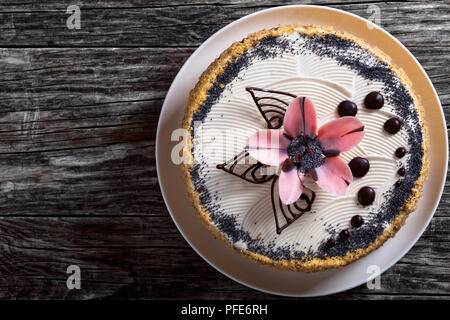 Deliziosa di semi di papavero, noci e uvetta pan di spagna con strati di crema e decorate con gocce di cioccolato e lo zucchero a velo di rosa fiori su un bianco d Foto Stock