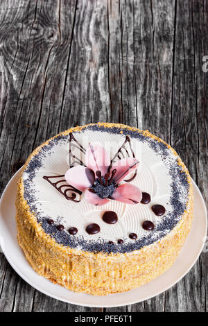 Lussureggianti pan di spagna con strati di crema e decorate con gocce di cioccolato e lo zucchero a velo di un bel colore rosa le orchidee sul piatto bianco in legno scuro Foto Stock