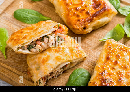 Fried flatbread avvolge farcite con carne di pollo, cetriolo, coleslaw, Pomodoro ,spinaci, aneto sul tagliere di legno, close-up, vista da sopra Foto Stock